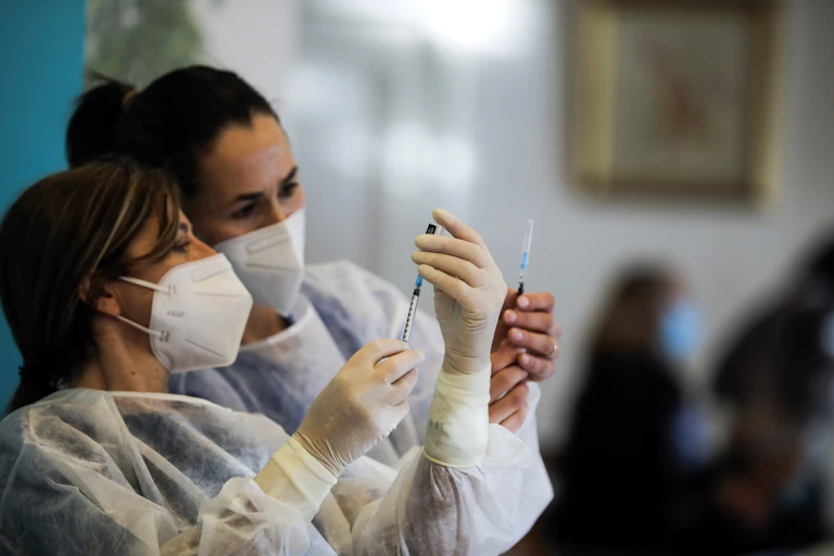 Healthcare workers prepare vaccines at a care home in Portugal