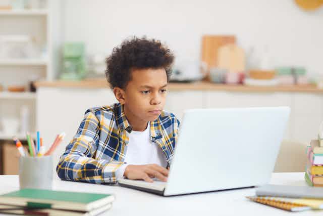 Boy concentrating looking at laptop at home