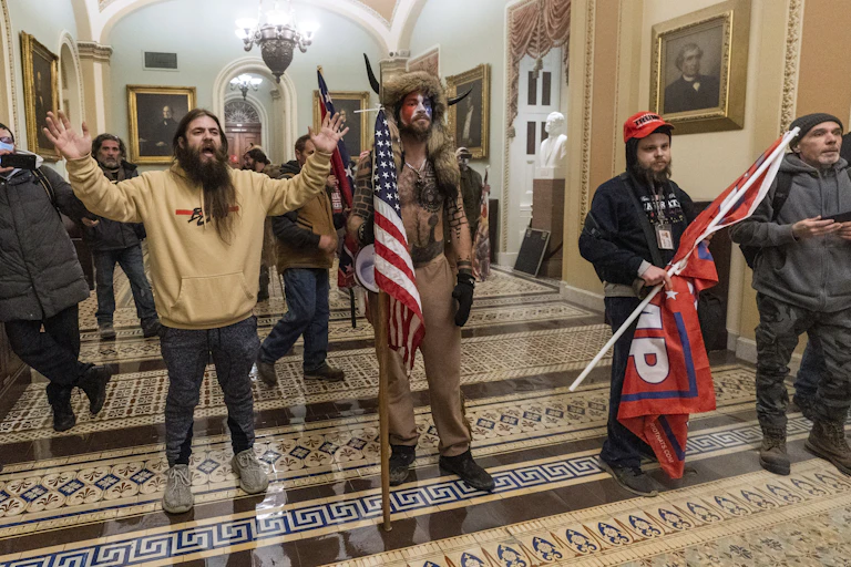Three pro-Trump rioters, one wearing an employee ID badge around his neck, are seen outside the Senate Chamber inside the Capitol on Jan. 6.