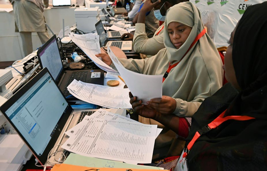 Niger's Independent National Electoral Commission officials sitting in front of laptops and papers with which they compile results of the Presidential election.  