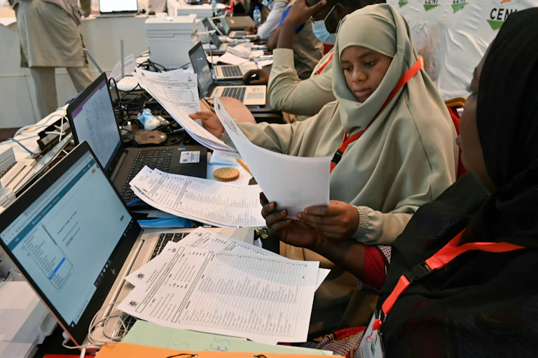 Niger's Independent National Electoral Commission officials sitting in front of laptops and papers with which they compile results of the Presidential election.