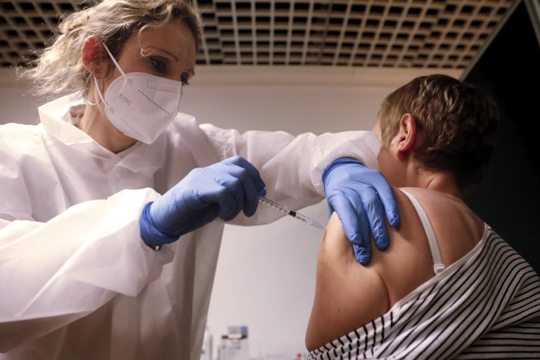 A health worker administers a COVID-19 vaccine to a woman