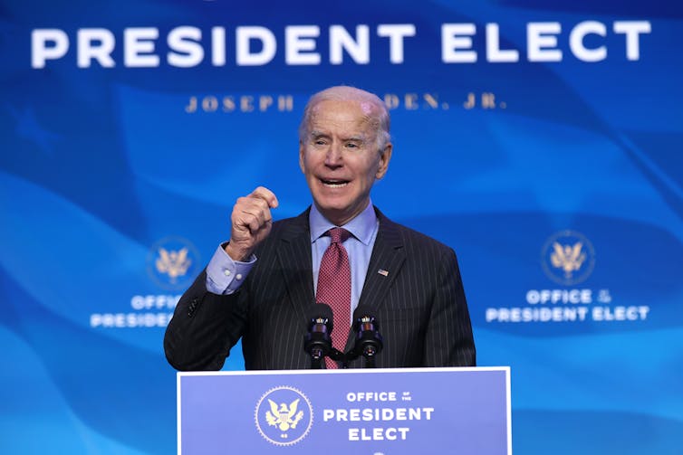 Joe Biden giving a speech under a sign that says 'President Elect.'