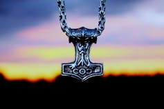 Pendant representing Thor's hammer, against the background of a colourful sunset.