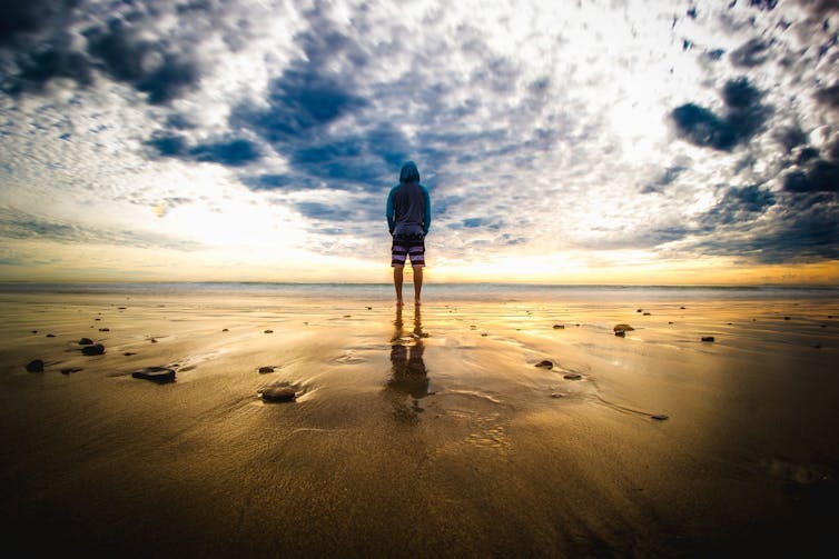 Man standing in front of sea with dramatic sky
