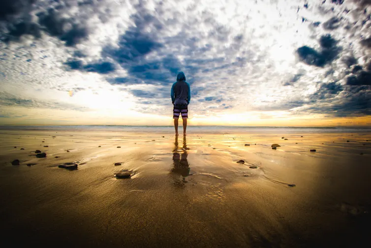 Man standing in front of sea with dramatic sky