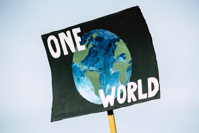 Black placard with 'one world' written on it.