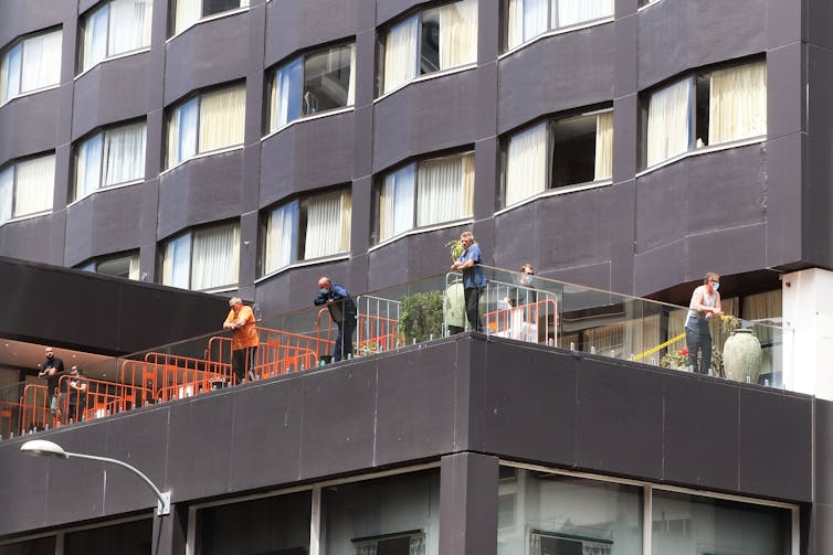 People in masks on hotel balcony