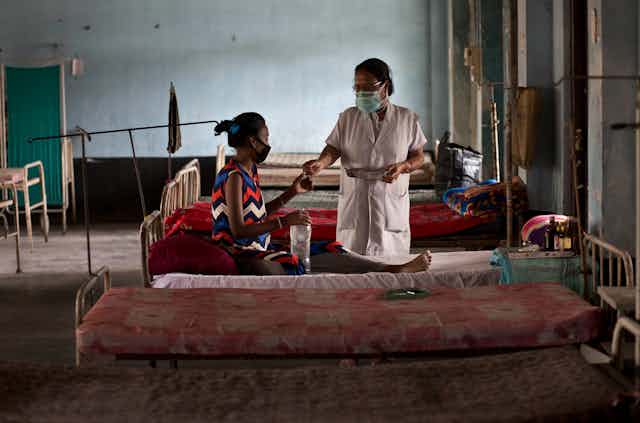 A woman receives TB medication in a clinic.