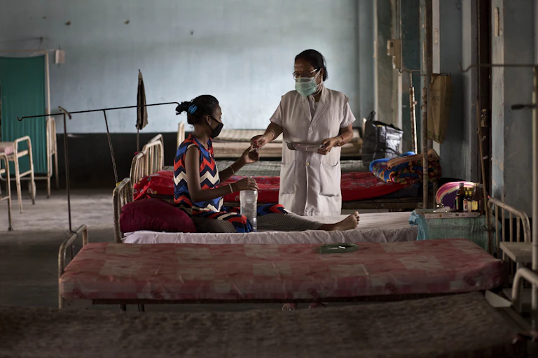 A woman receives TB medication in a clinic.