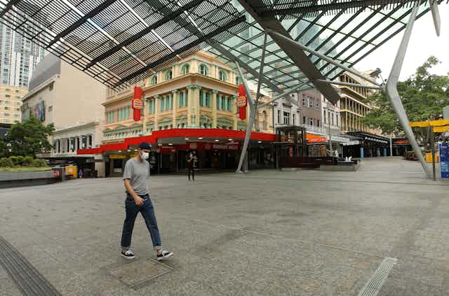 Person wearing a mask walking through deserted Brisbane streets