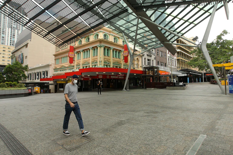 Person wearing a mask walking through deserted Brisbane streets