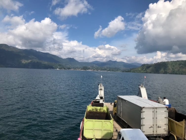 A boat in the middle of a lake with two men onboard.
