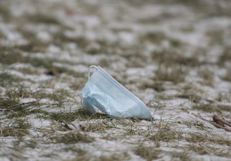 A crumpled blue face mask on the ground