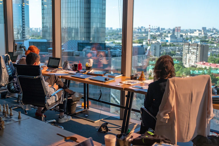 Office workers sit at desks gazing out of window.