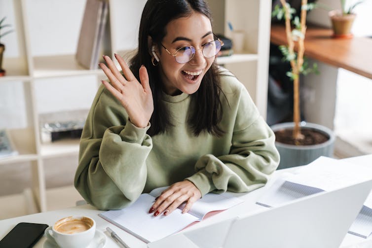 Happy teenager waving at computer