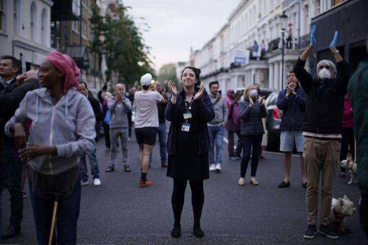 La gente se para en una calle de Londres y aplaude.