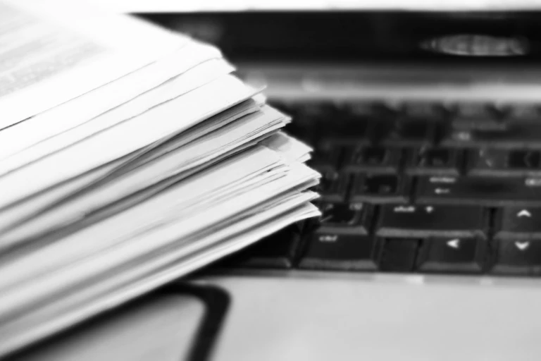 A close-up of a stack of papers and a keyboard