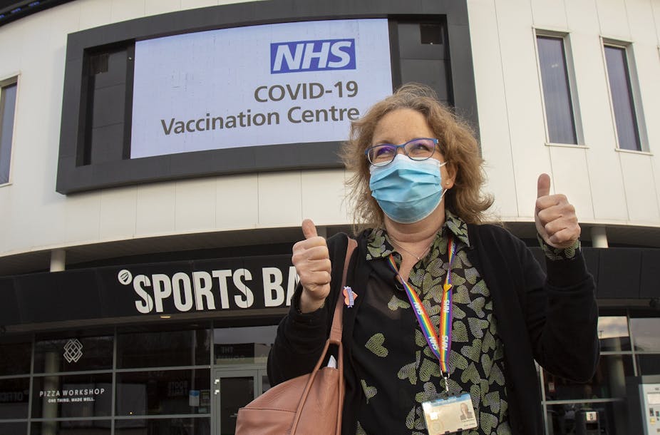 A woman leaving a UK vaccination centre, giving thumbs up