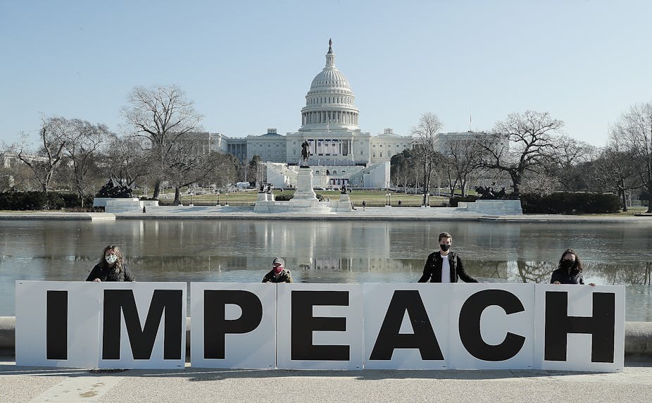 Impeachment, People gather, with the U.S. Capitol in the background with large a large sign saying 'impeach'