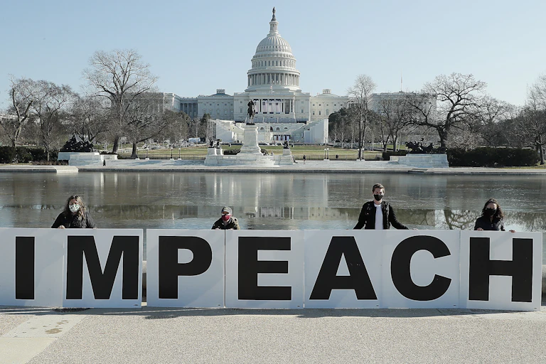 Impeachment, People gather, with the U.S. Capitol in the background with large a large sign saying 'impeach'