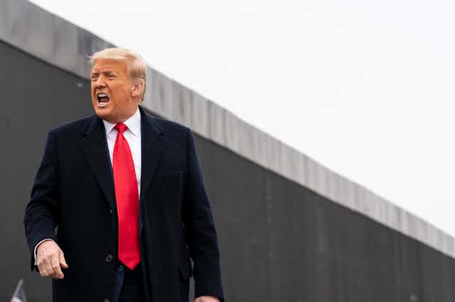 Trump yells while standing in front of a border wall in Texas.