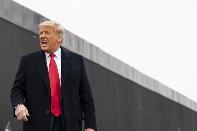 Trump yells while standing in front of a border wall in Texas.