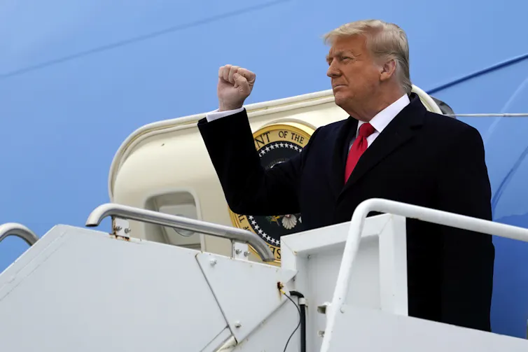 Trump raises his fist as he steps off Air Force One.
