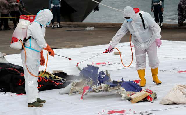 Workers disinfect parts of Sriwijaya Air Flight 182 recovered from the waters off Jakarta, Indonesia, January 10 2021.