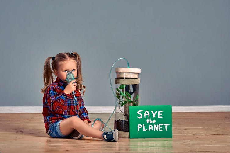 Girl in breathing mask attached ot plant in container