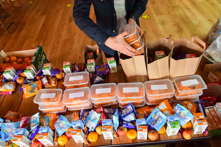 A man packs brown bags of food for families in need.