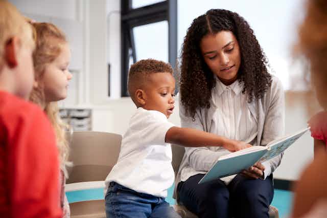 Nursery worker reading book with young boy