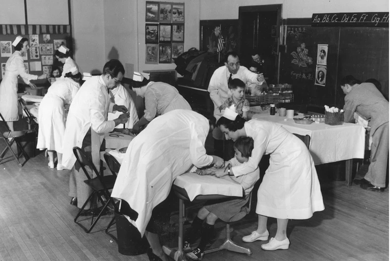 medical workers give kids polio shots in a classroom
