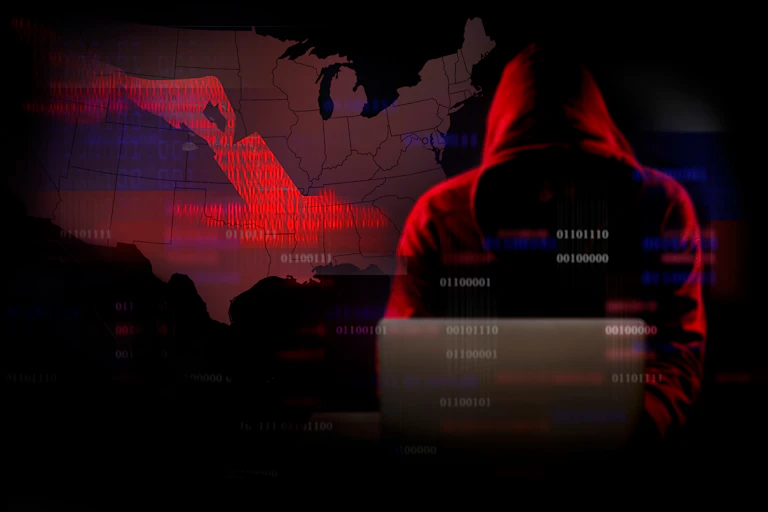 Hooded man on laptop codes in front of map of USA