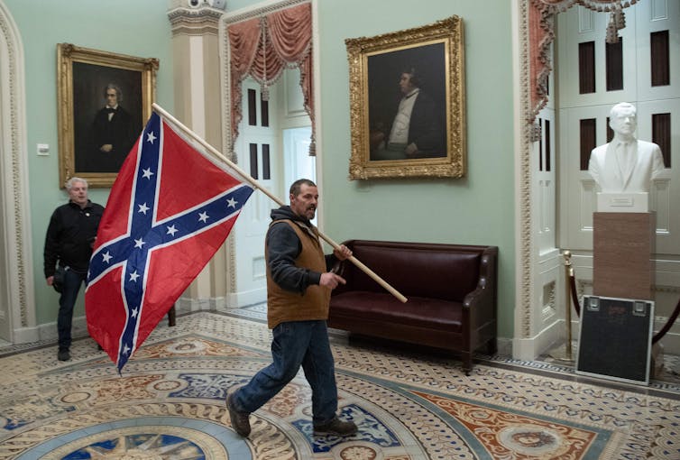 Un hombre lleva la bandera de batalla de la Confederación en el Capitolio de los Estados Unidos.
