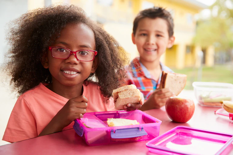Two children eating packed lunches