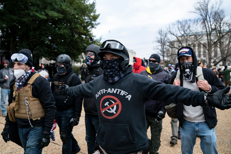 Man wearing black helmet, goggles and face scarf stretches out his arms