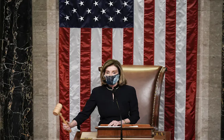 Nancy Pelosi, in a mask, lowers the gavel.