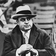 Al Capone in a fedora and a coat and tie.