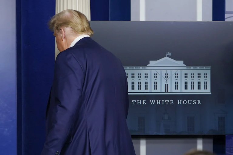 Trump walks out of the press briering room at the White House.