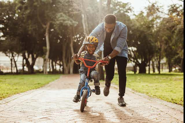 Picture of a man teaching his child to ride a bike.
