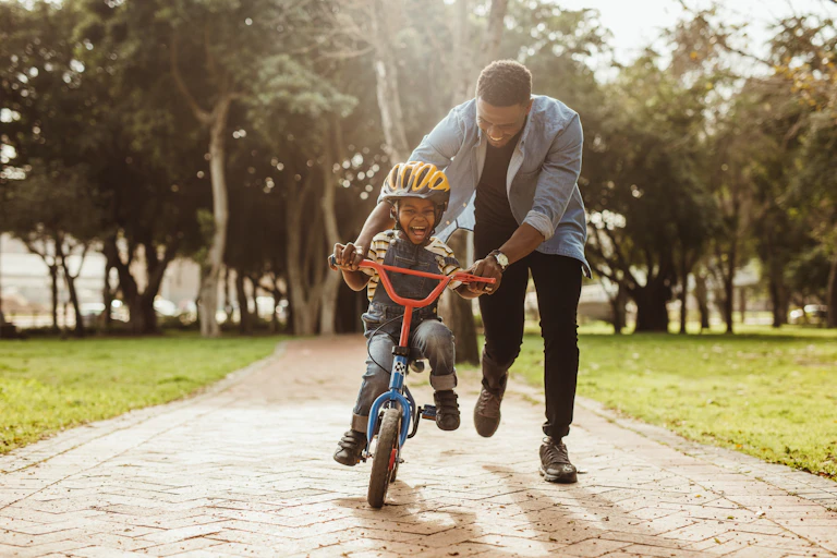Picture of a man teaching his child to ride a bike.