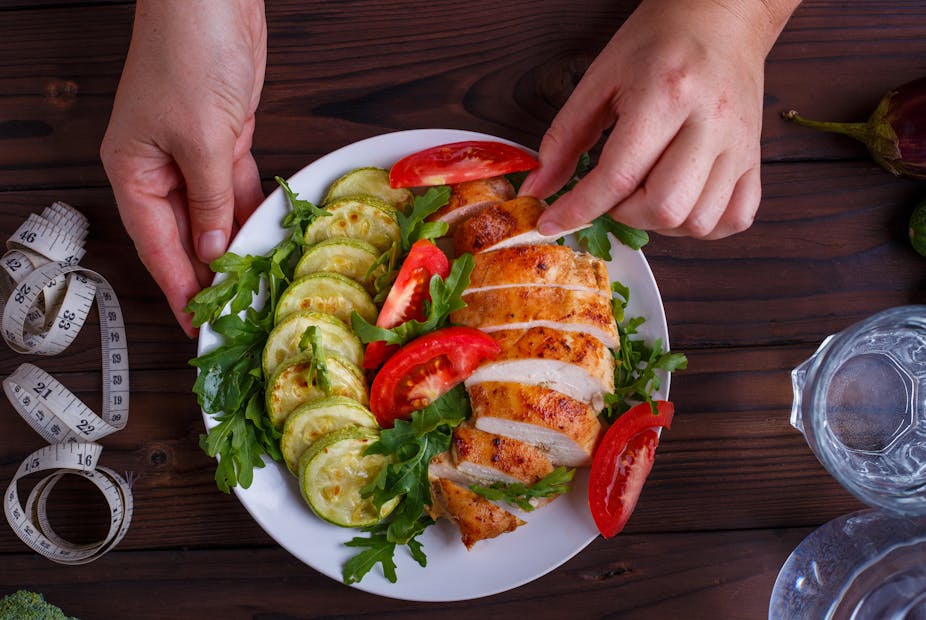 Person prepares a healthy meal of courgette, tomatoes, rocket, and chicken.