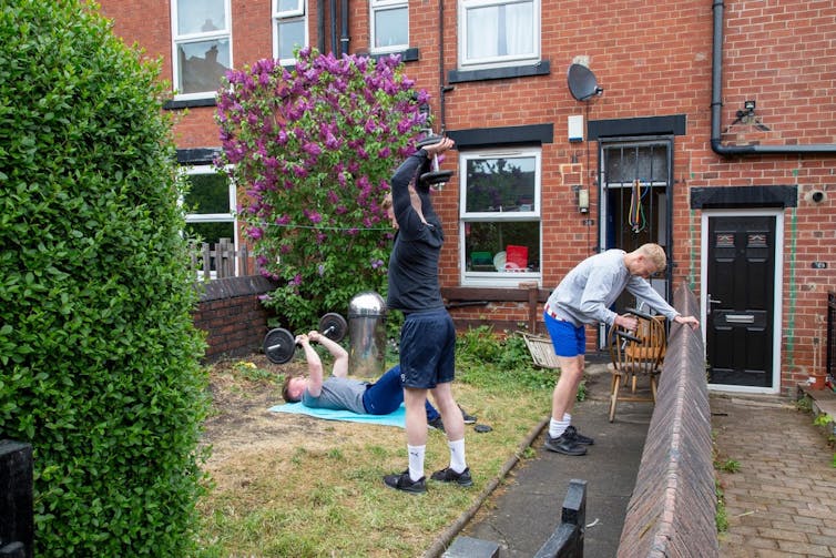 Three men work out in their garden 'gym' during lockdown.