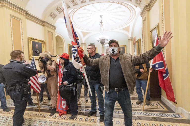 Rioters carrying white supremacist symbols inside the Capitol