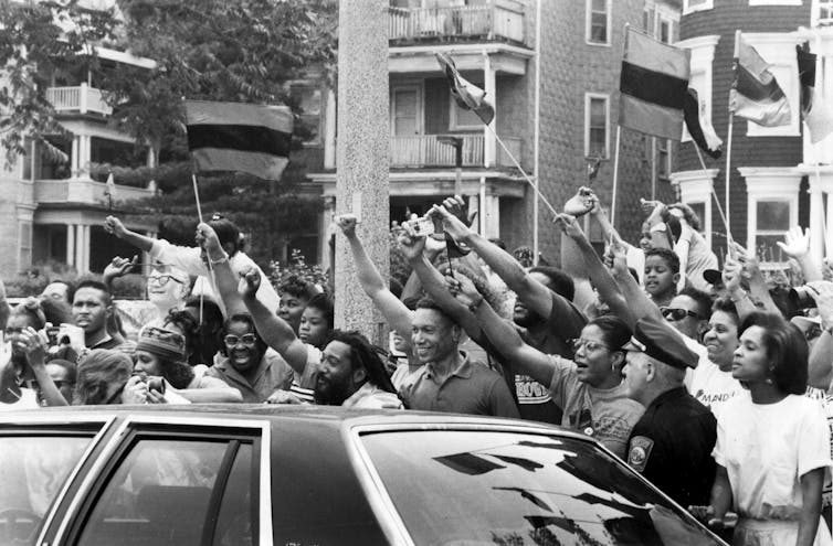 Black-and-white image of Black people cheering for Nelson Mandela.