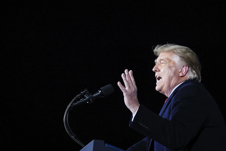 Trump speaks from a lectern while motioning with his hand.