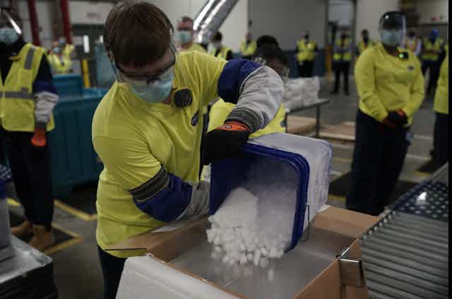 A worker pours dry ice into boxes containing Pfizer's COVID-19 vaccine.