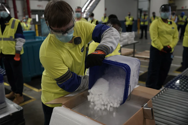 A worker pours dry ice into boxes containing Pfizer's COVID-19 vaccine.