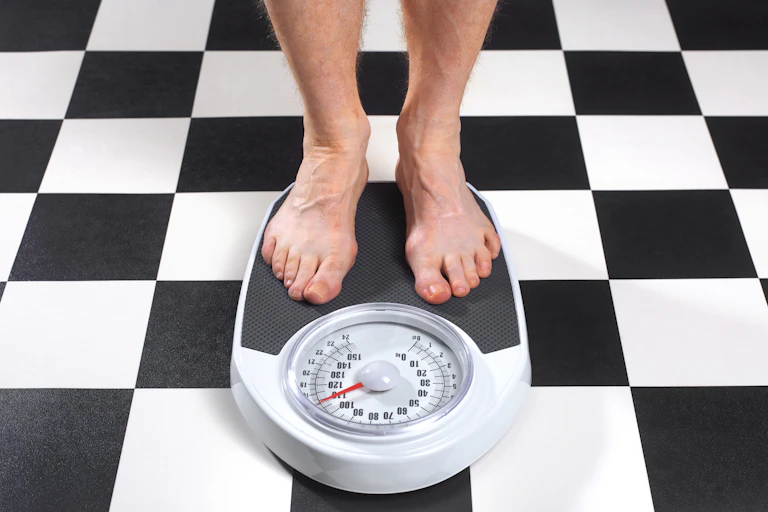 A man stands on a bathroom scale.